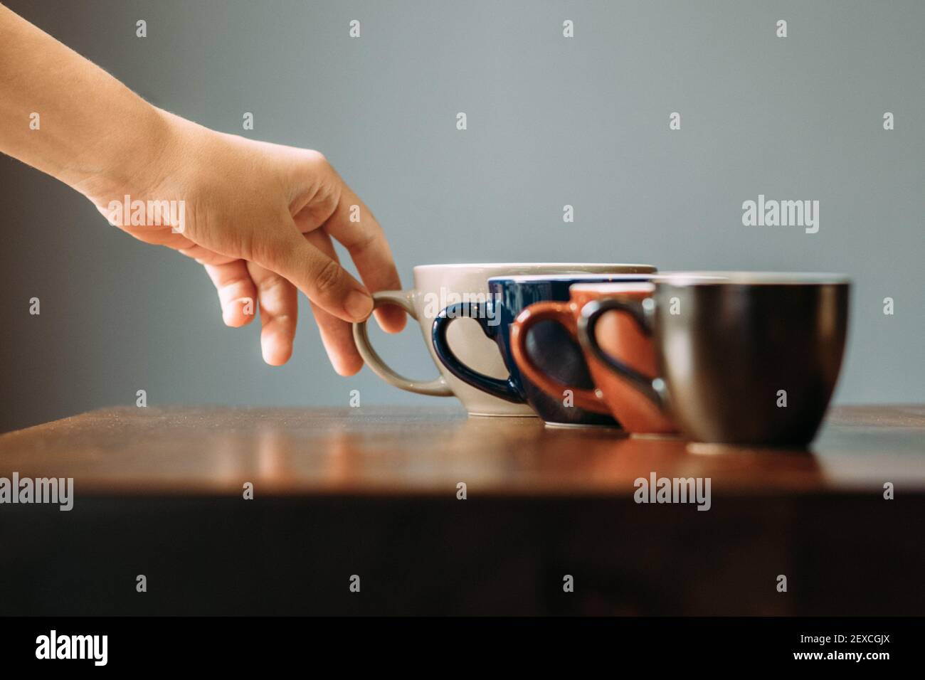 Tasses de café dans une rangée avec une main atteignant pour elles Banque D'Images Tasses de café dans une rangée avec une main atteignant pour elles Banque D'Images