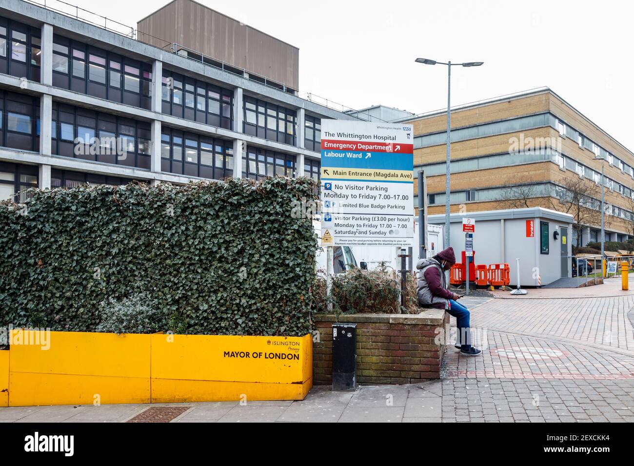 Un homme attend devant l'entrée du service des accidents et des urgences de l'hôpital de Whittington sur Highgate Hill, Islington, Londres, Royaume-Uni Banque D'Images