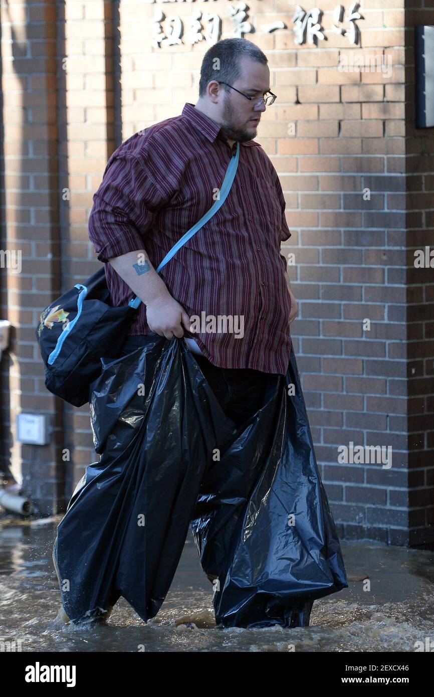 Un homme utilise des sacs poubelle pour protéger ses chaussures et ses  pantalons lorsqu'il marche à travers les inondations après une coupure  d'eau principale a causé l'inondation de l'eau boueuse à l'angle