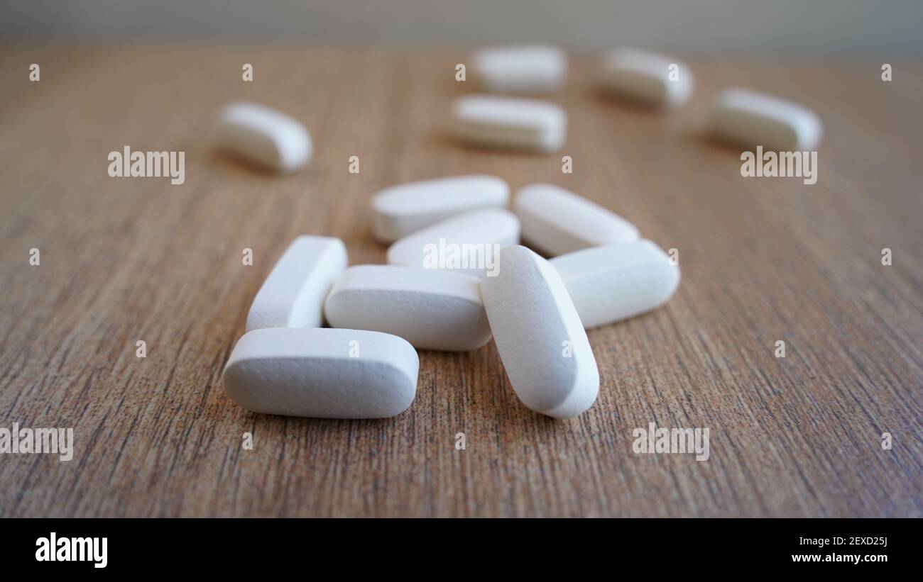 Tas de calcium, comprimés de supplément de vitamine isolés sur fond de bois. Beaucoup de pilules médicales blanches et capsules pour les os forts. Restez en sécurité et en santé Banque D'Images