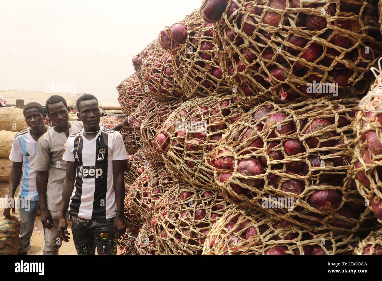 Les commerçants posent devant des sacs d'oignons disposés sur le marché alimentaire de Lagos, dans le district Mile-12 de Lagos, au Nigeria. Banque D'Images
