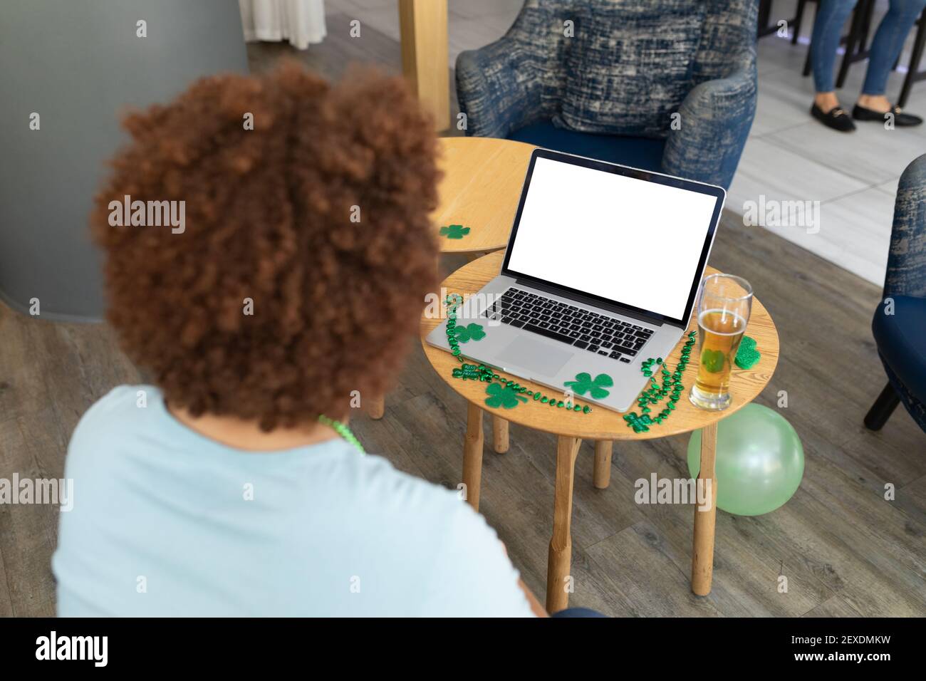 Femme de course mixte célébrant la journée de St patrick sur PC portable appel avec espace de copie à l'écran Banque D'Images