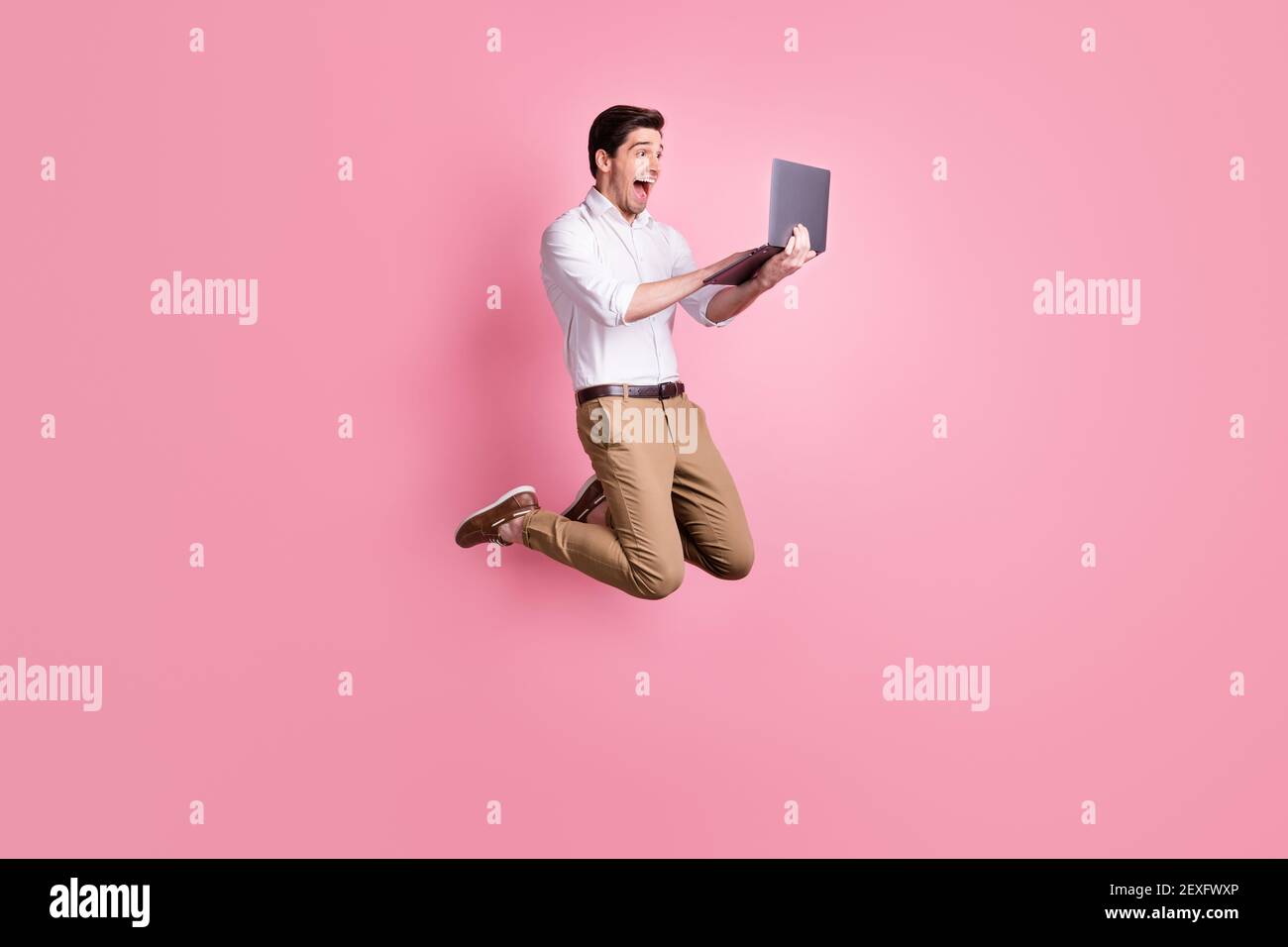 Portrait plein écran d'un homme hurlant qui saute en tenant ordinateur  portable isolé sur fond rose pastel Photo Stock - Alamy