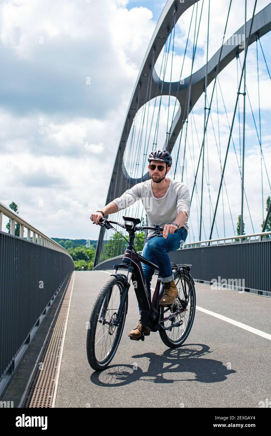 Cycliste sur vélo électrique traverse le pont East Harbour Bridge à Francfort-sur-le-main, Hessen, Allemagne. Banque D'Images
