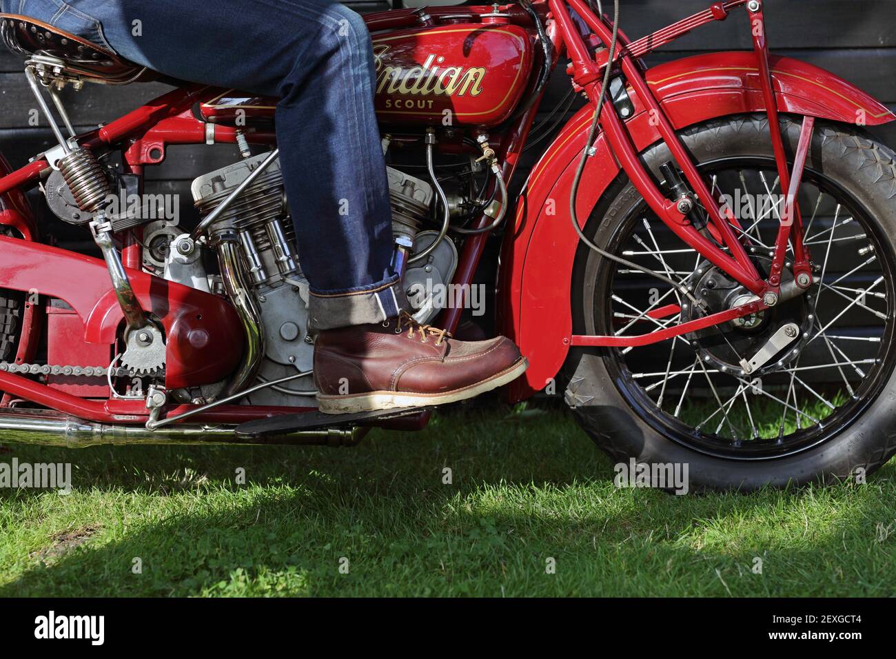 Gros plan sur un motard vintage portant un Jean et des bottes rouges à motif ailes. Banque D'Images