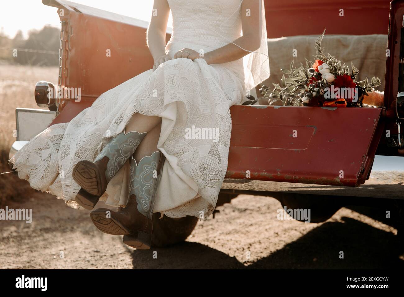 Mariée dans la robe de mariage assis dans le camion de camion rouge dans les bottes de cow-boy. Banque D'Images