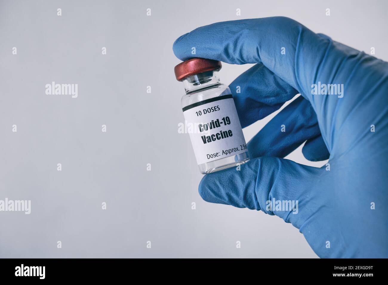 Main dans un gant bleu contenant le flacon du vaccin Covid-19 Banque D'Images