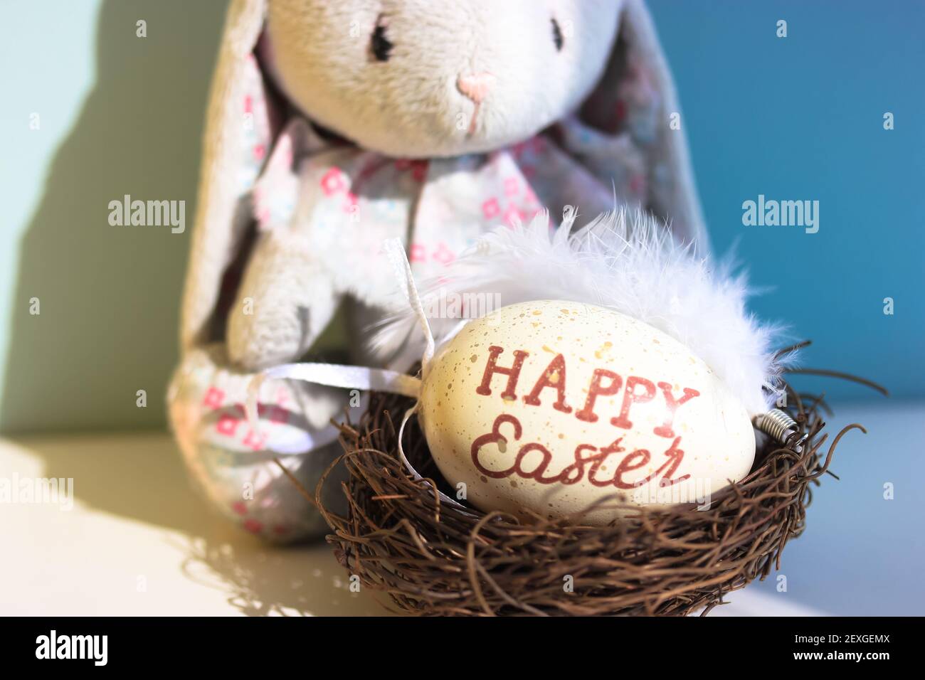 Un joli lapin en peluche triste sur fond bleu et un nid avec un œuf de  Pâques à l'intérieur. Jeu de chasse aux œufs pour les enfants Photo Stock -  Alamy
