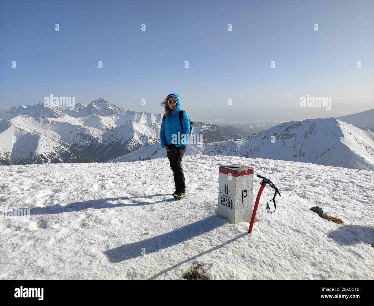 Un bon touriste dans une veste bleue sur un sommet de montagne par une belle journée ensoleillée. Banque D'Images