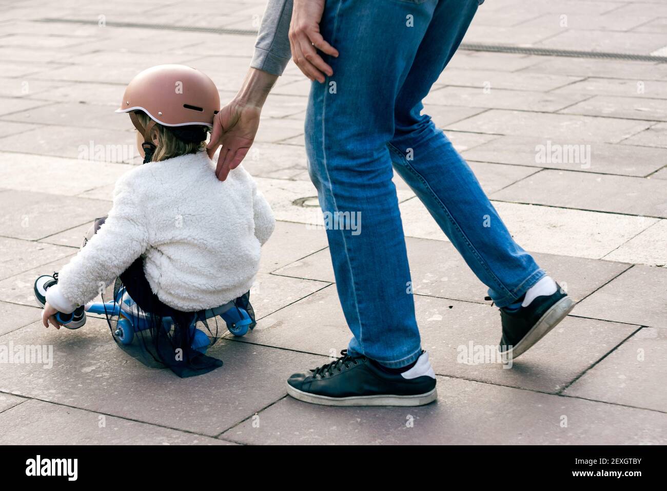 Petite fille blanche de 3-4 ans sur un scooter de la couche avec son père  aidant Photo Stock - Alamy