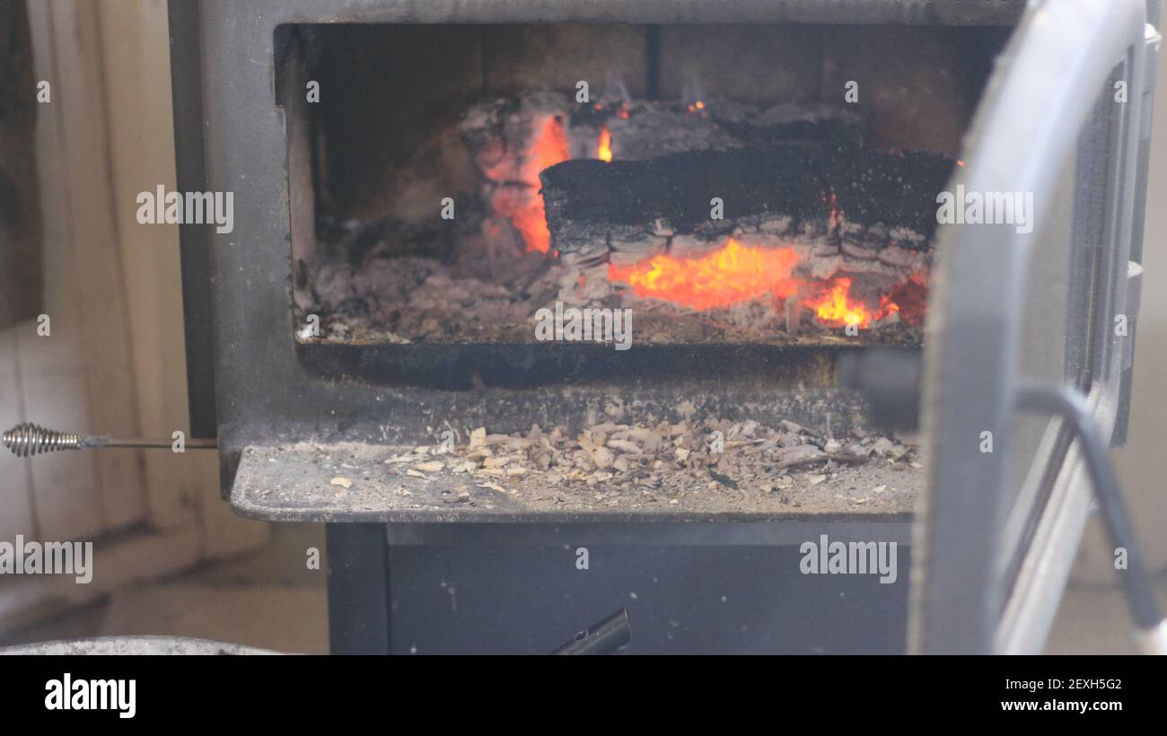 Ajouter du bois dans un poêle à bois pendant les mois d'hiver froids. Banque D'Images