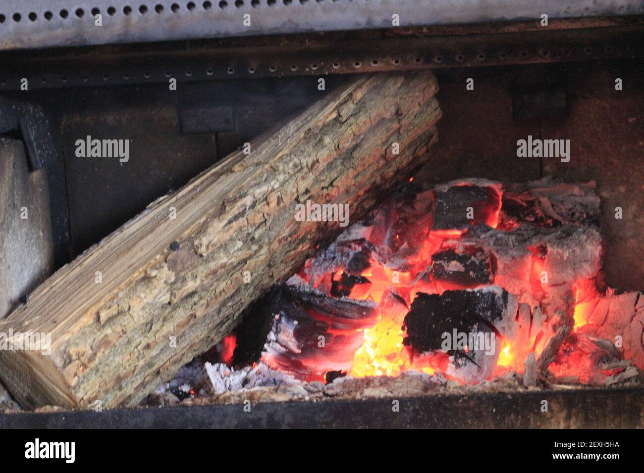 Ajouter du bois dans un poêle à bois pendant les mois d'hiver froids. Banque D'Images