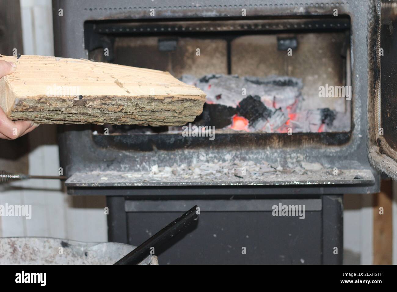 Ajouter du bois dans un poêle à bois pendant les mois d'hiver froids. Banque D'Images