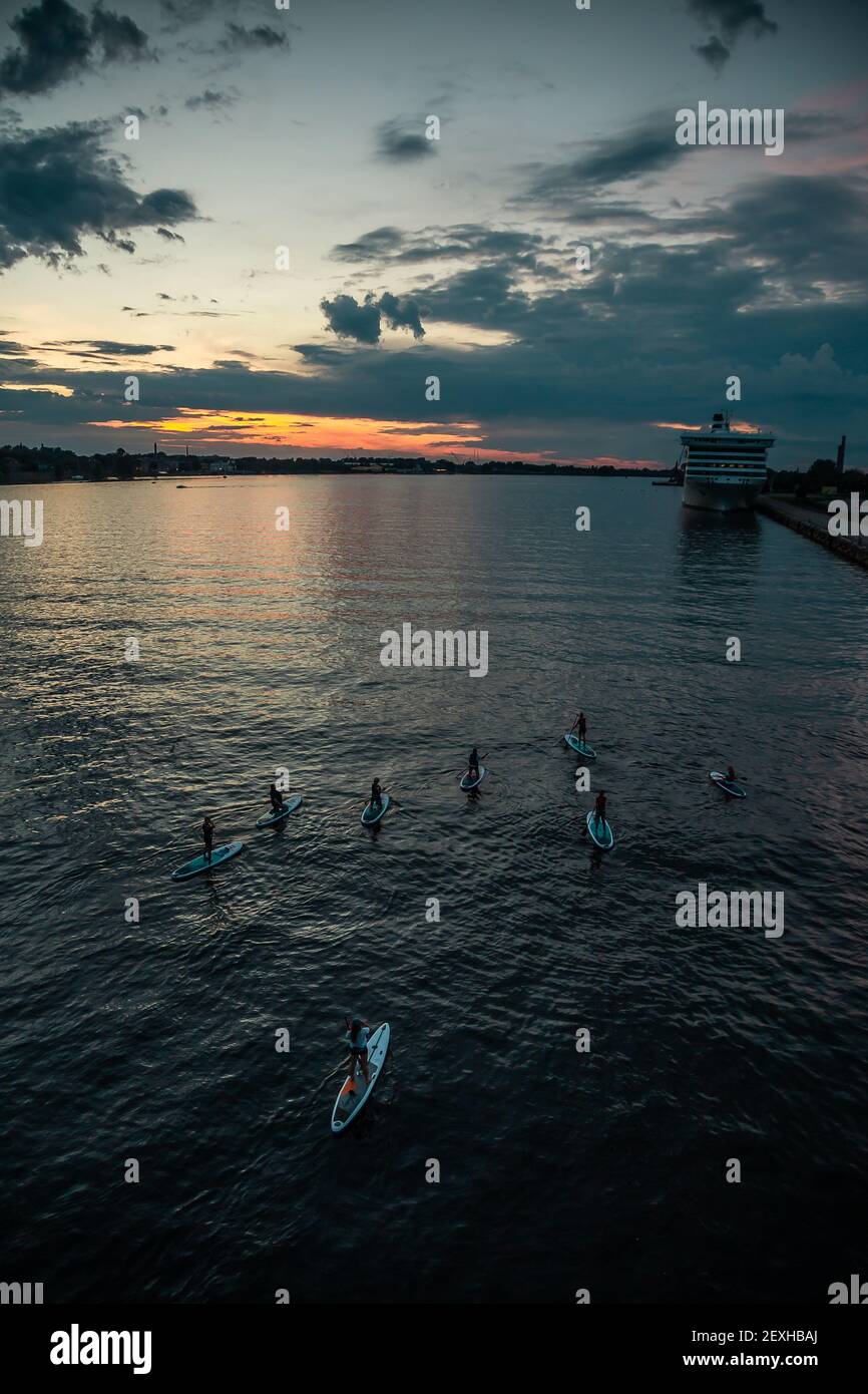 Un groupe de personnes qui s'amusent à pagayer avec des paddleboards debout à l'intérieur la rivière au coucher du soleil Banque D'Images