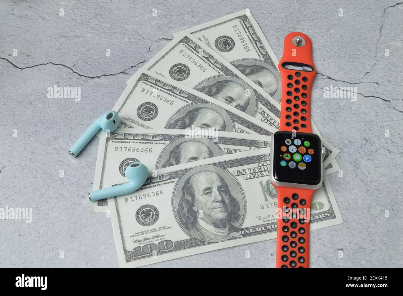 Klang,Malaisie: 5 mars 2021- une montre de pomme, des écouteurs et des billets de banque sur fond gris Banque D'Images
