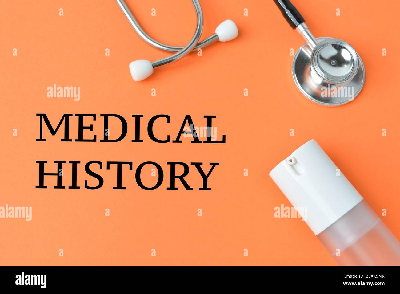 Désinfectant pour les mains, stéthoscope sur fond orange écrit avec DES ANTÉCÉDENTS MÉDICAUX. Banque D'Images