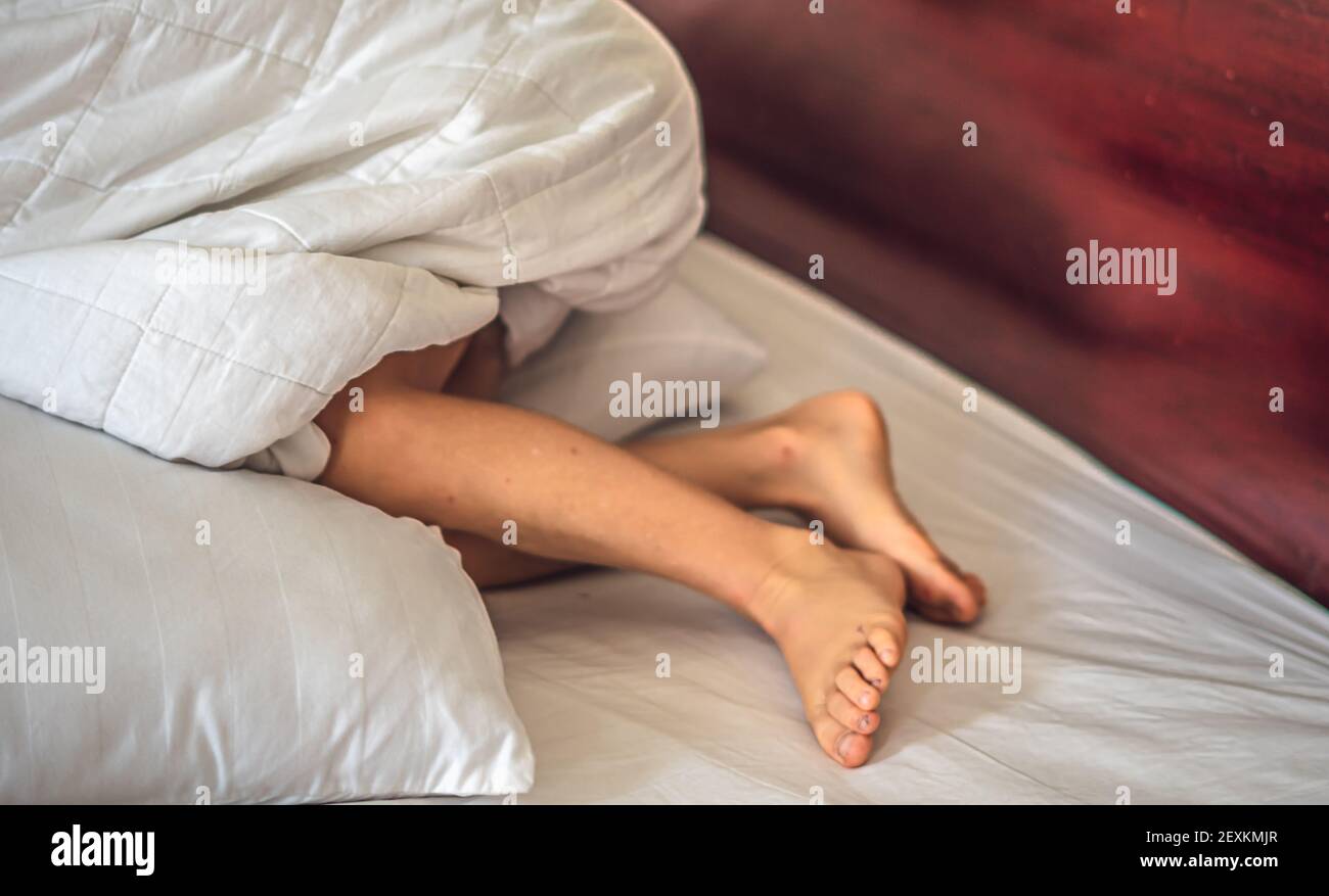 Vue Rapprochee De Cote Enfant Garcon Jambe Genoux Pieds Se Collent Sous La Couverture Blanche Sur Le Lit Concept De Sommeil Et De Detente Tendresse Du Reve De Bebe Du Matin Ou