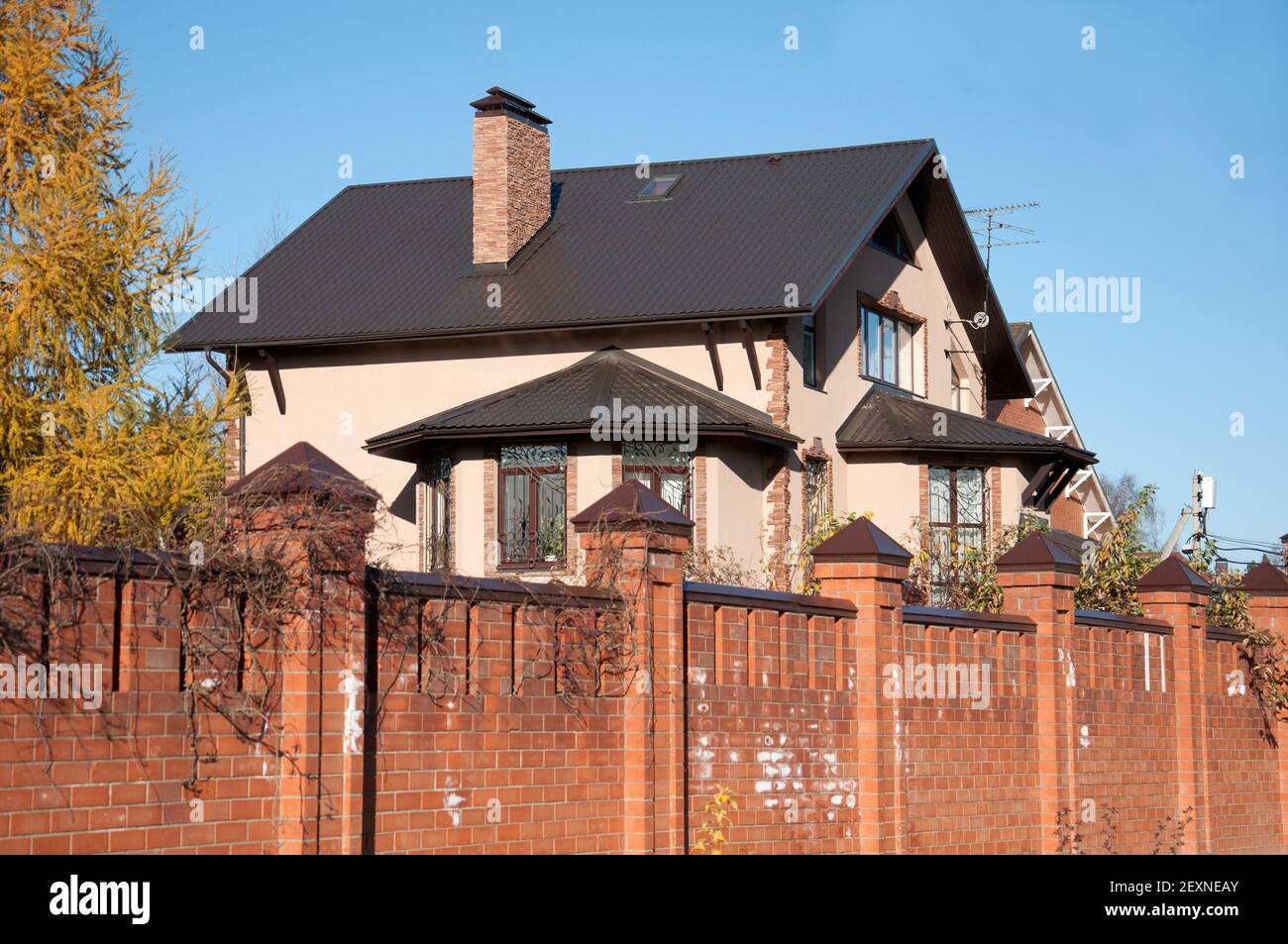 Un cottage de deux étages en briques rouges avec une clôture Banque D'Images