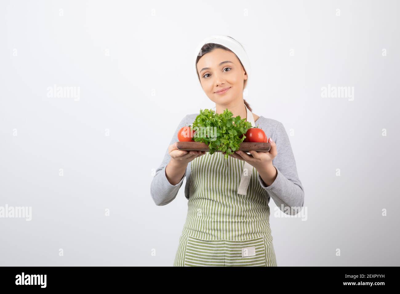 Image d'une belle femme attrayante tenant une planche en bois avec persil Banque D'Images