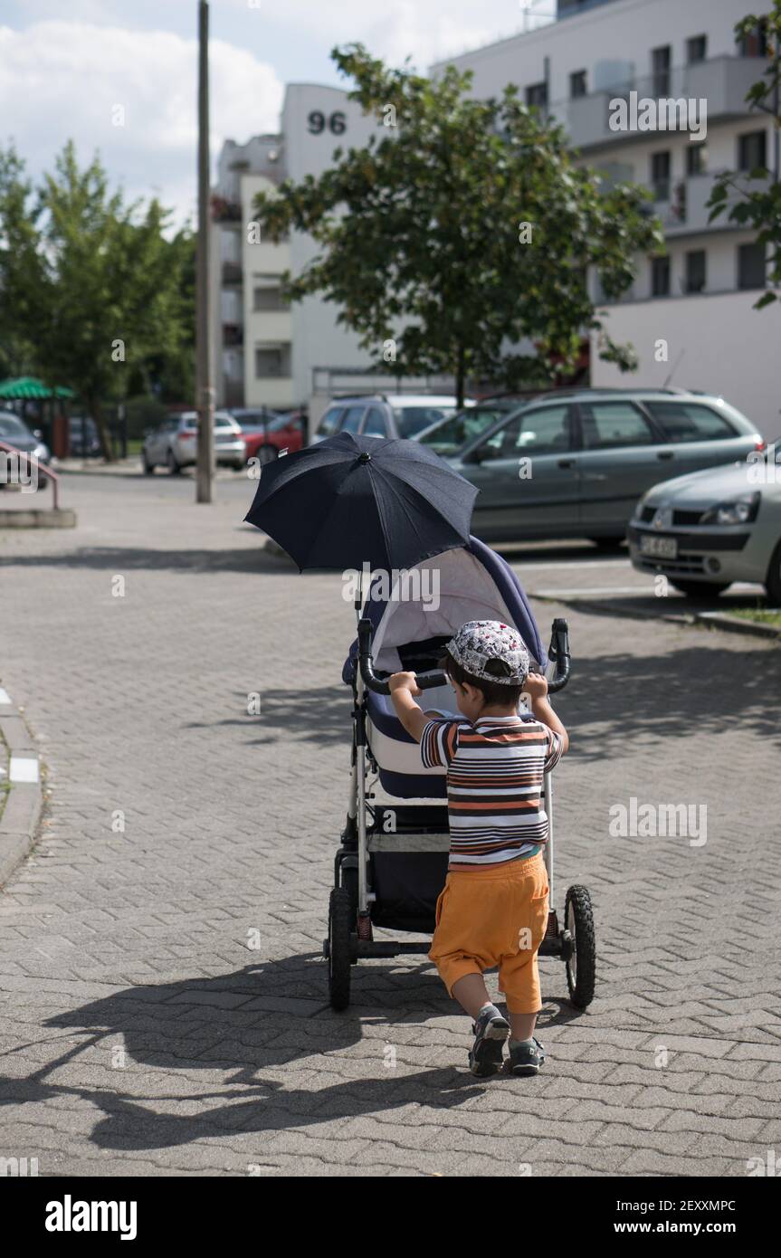 Poznan Pologne 06 Aout 17 Un Jeune Garcon Pousse Une Poussette Avec Bebe Sur Un Trottoir Photo Stock Alamy