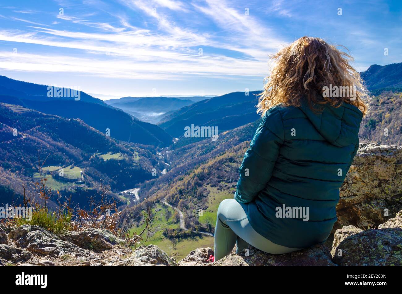 Femme blonde aux cheveux bouclés, assise sur un banc, regardant les vues fantastiques sur les montagnes des Ribes, dans la région de Ripolles, Gérone Banque D'Images