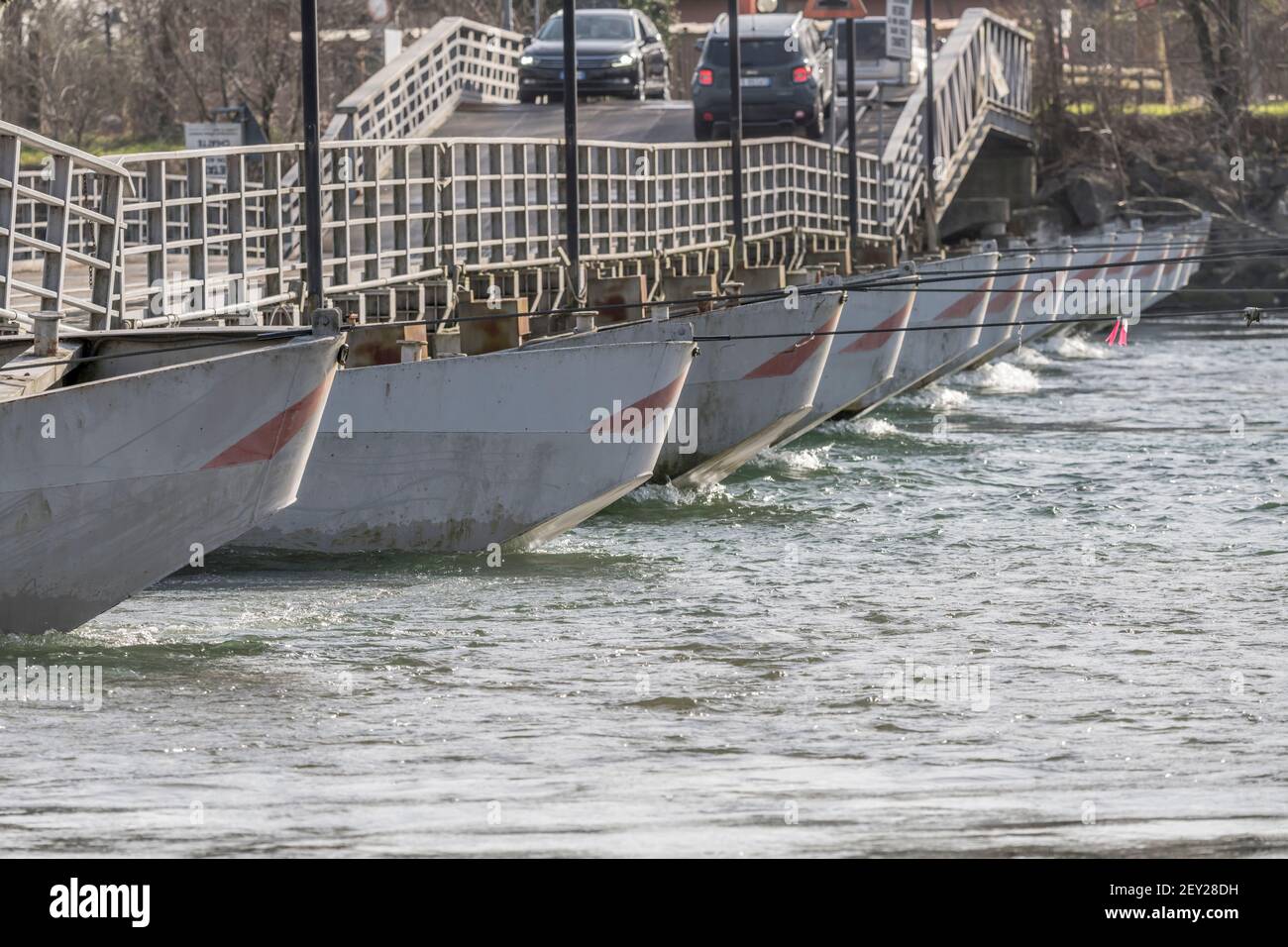 Rangée de prows au pont ponton sur les eaux claires de la rivière Ticino, tiré par un beau jour d'hiver à Bereguardo, Pavie, Lombardie, Italie Banque D'Images