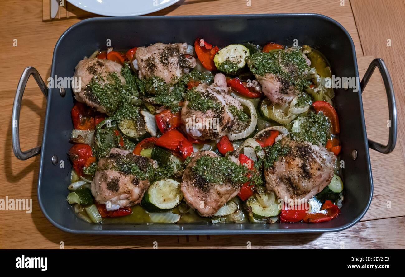 Plateau de cuisson de cuisses de poulet rôties avec garniture aux herbes et légumes, y compris courgettes et poivrons rouges, dans un plat à rôtir Banque D'Images