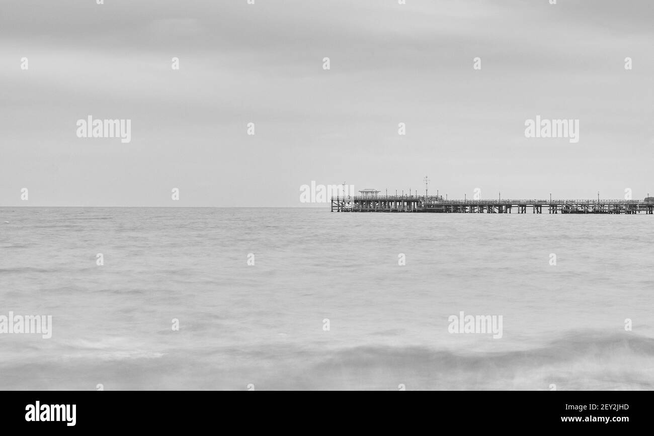 Une image de beaux-arts noir et blanc de Swanage Pier sur une mer lisse et immobile Banque D'Images