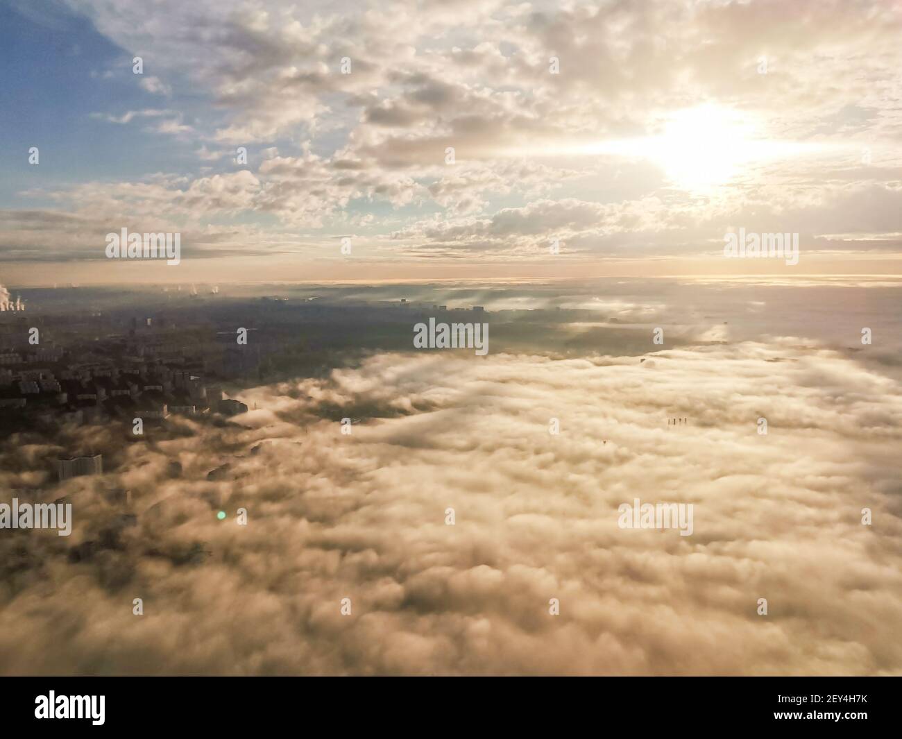 Concept de voyage. Une vue magnifique de l'avion au soleil, nuages aérés polyvolumétriques multicolores, gratte-ciel de la ville en dessous, vue de dessus. Magnifique natura Banque D'Images