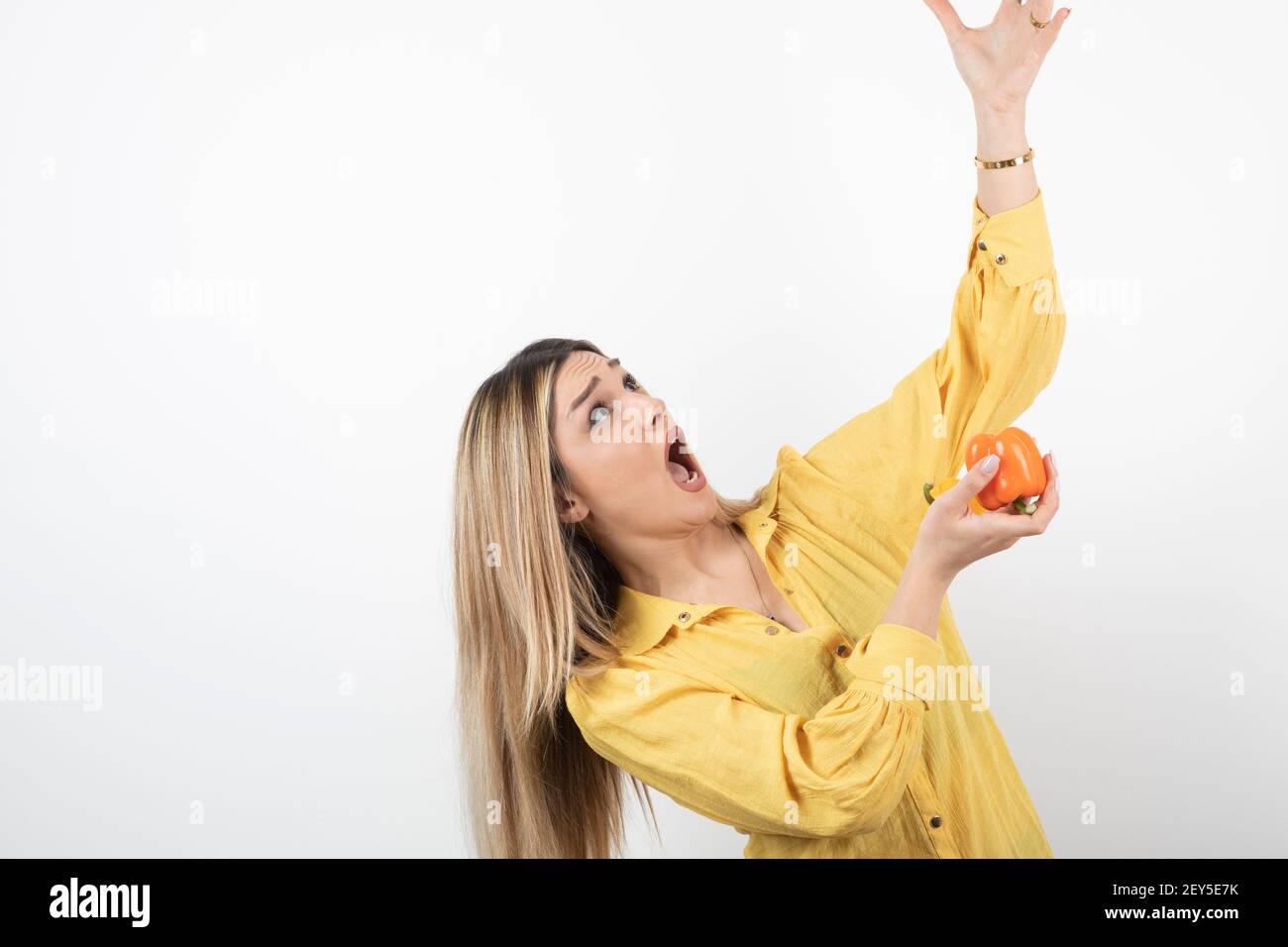 Photo d'une femme choquée avec du poivron en regardant quelque chose sur fond blanc Banque D'Images