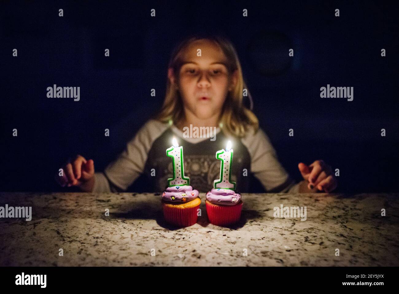 Tween fille soufflant des bougies sur deux cupcakes avec le visage pas dans le focus Banque D'Images