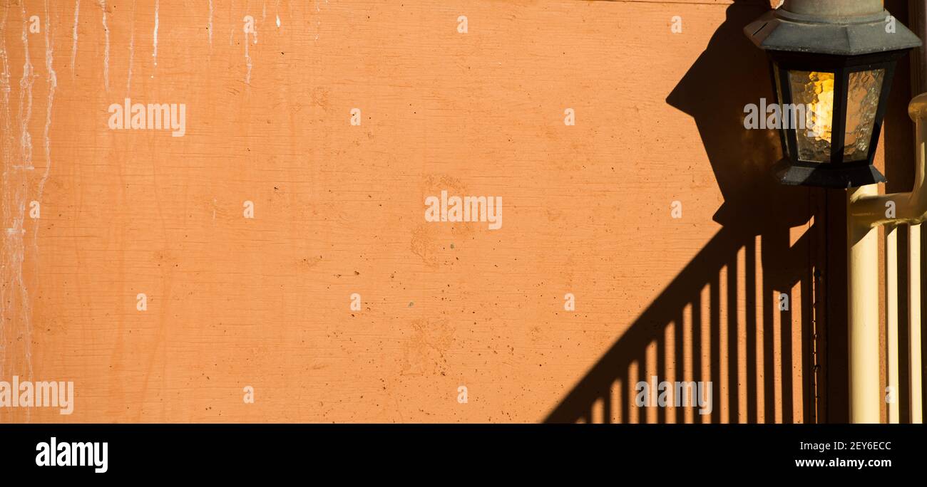 lampe extérieure ou lanterne contre blanc orange pêche couleur maison extérieure ciment mur texturé avec ombre de la rampe d'escalier dans le coin inférieur Banque D'Images