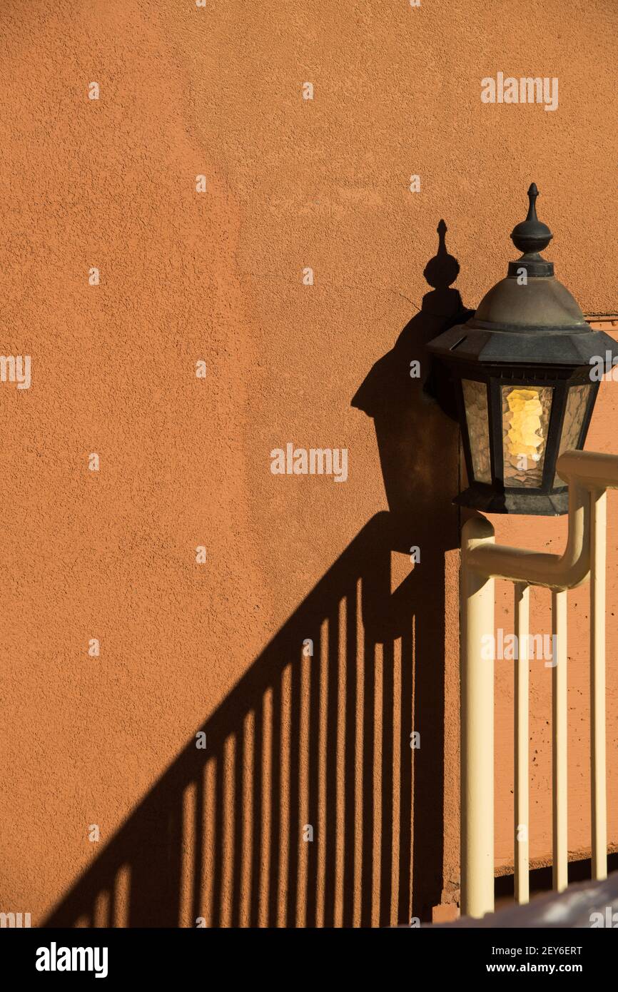 lampe extérieure ou lanterne contre blanc orange pêche couleur maison extérieure ciment mur texturé avec ombre de la rampe d'escalier dans le coin inférieur Banque D'Images