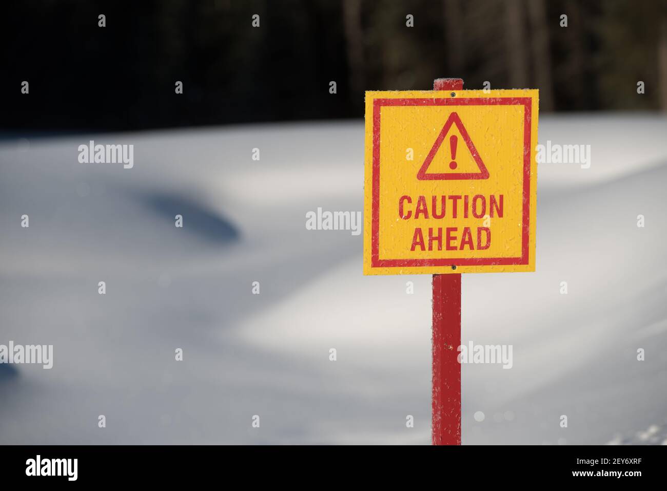 attention, signe triangle avec point d'exclamation dans la neige jaune et rouge en arrière-plan avertissant de la glace mince devant l'étang sur le terrain de golf en hiver Banque D'Images