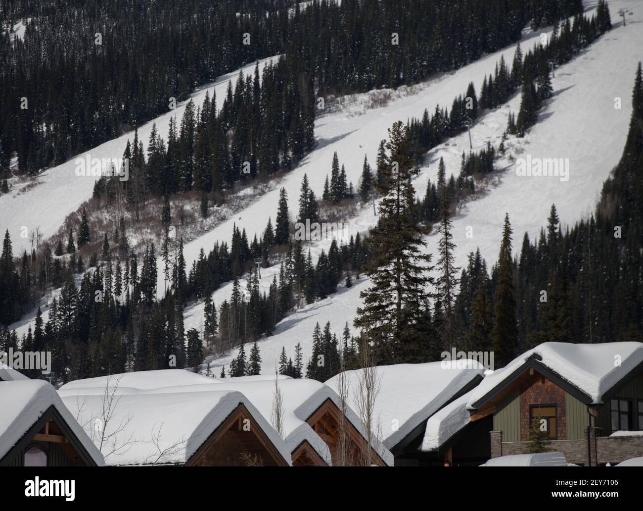Les toits enneigés des chalets de ski de la station de ski de SunPeaks, en Colombie-Britannique, sont recouverts de pistes enneigées en arrière-plan, les arbres sont disposés sur les pentes horizontales Banque D'Images
