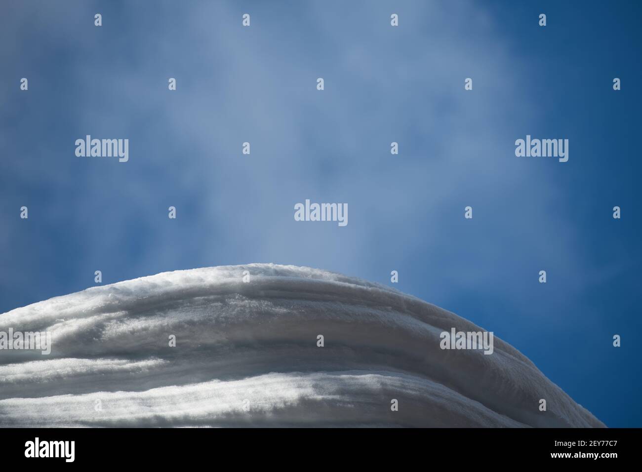 couches de neige accrochées à la maison ou chalet de ski toit ciel bleu avec des nuages sombres en arrière-plan sur les hivers clairs jour type espace horizontal Banque D'Images