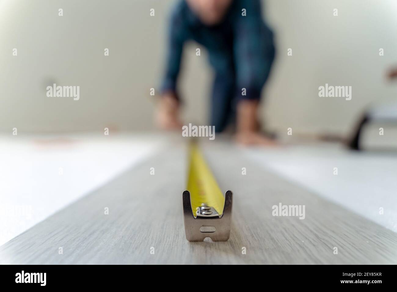 Gros plan d'un mètre pour mesurer un plancher en bois. Homme mesurant hors foyer Banque D'Images