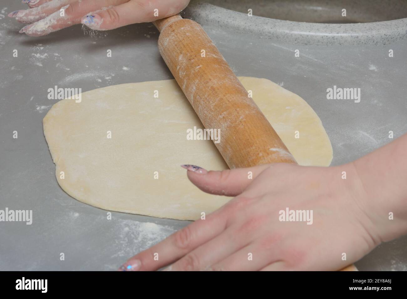 Faire cuire les rouleaux de pâte à l'aide d'un rouleau en bois. Faire de la pizza ou des boulettes maison. Gros plan, mise au point sélective. Banque D'Images