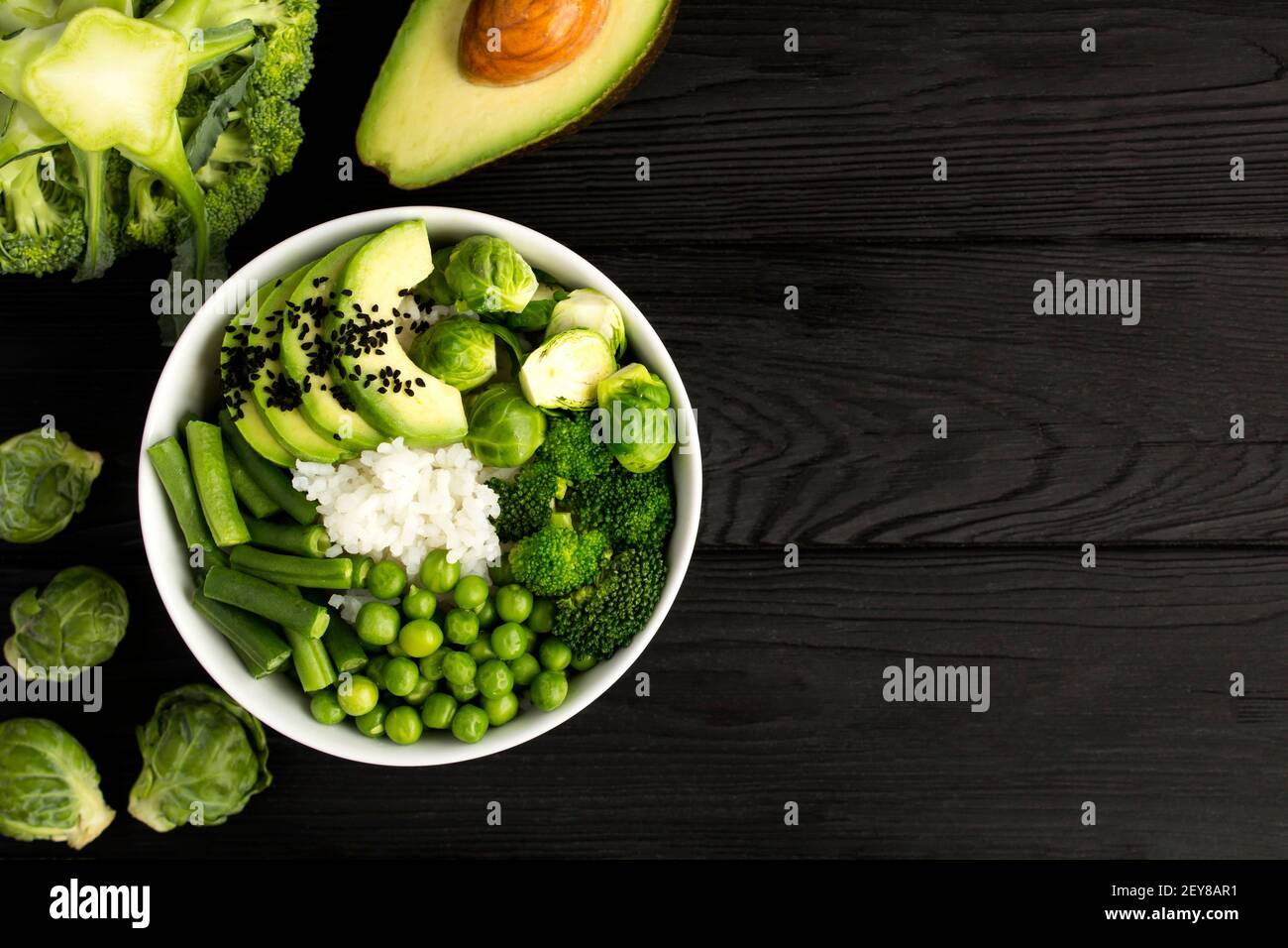 Bol à poke végétalien avec du riz blanc et des légumes verts dans le bol blanc sur fond de bois noir.vue du dessus. Copier l'espace. Banque D'Images