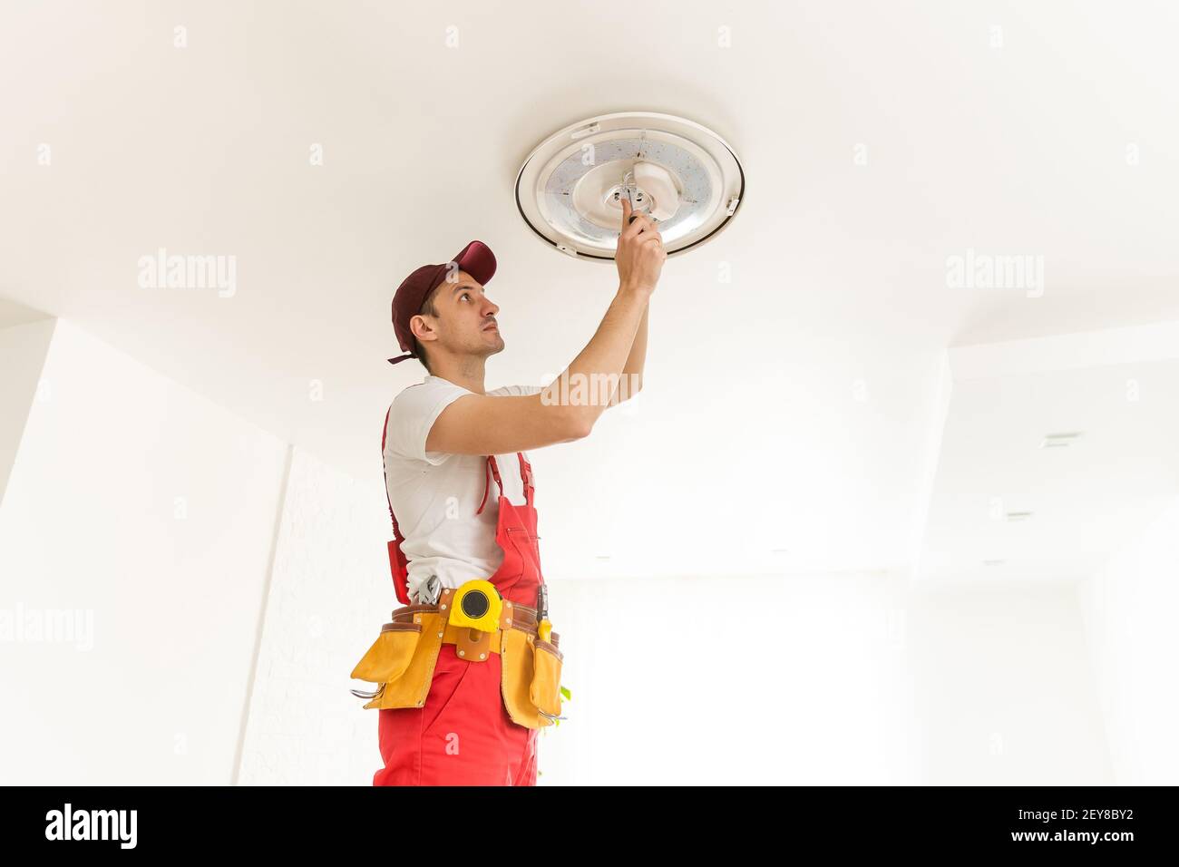 Un électricien installe un lustre au plafond. Concept de construction Banque D'Images