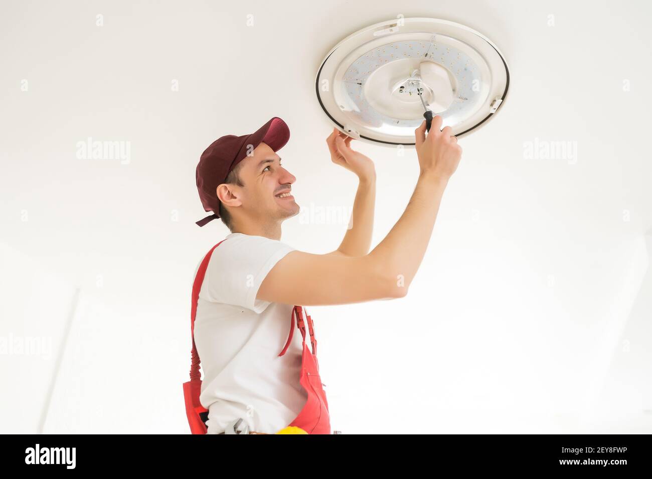 Un électricien installe un lustre au plafond. Concept de construction Banque D'Images