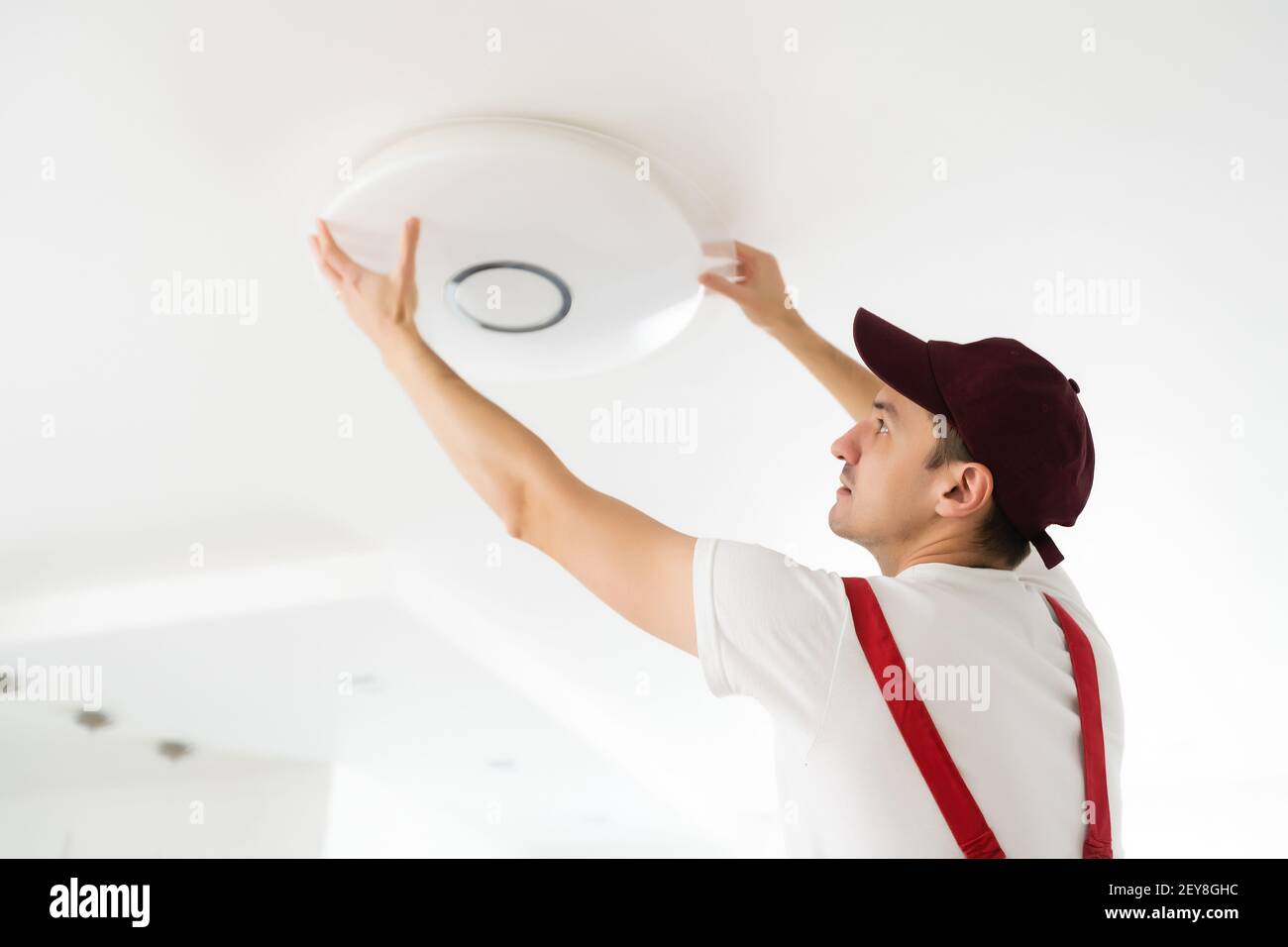 Un électricien installe un lustre au plafond. Concept de construction Banque D'Images