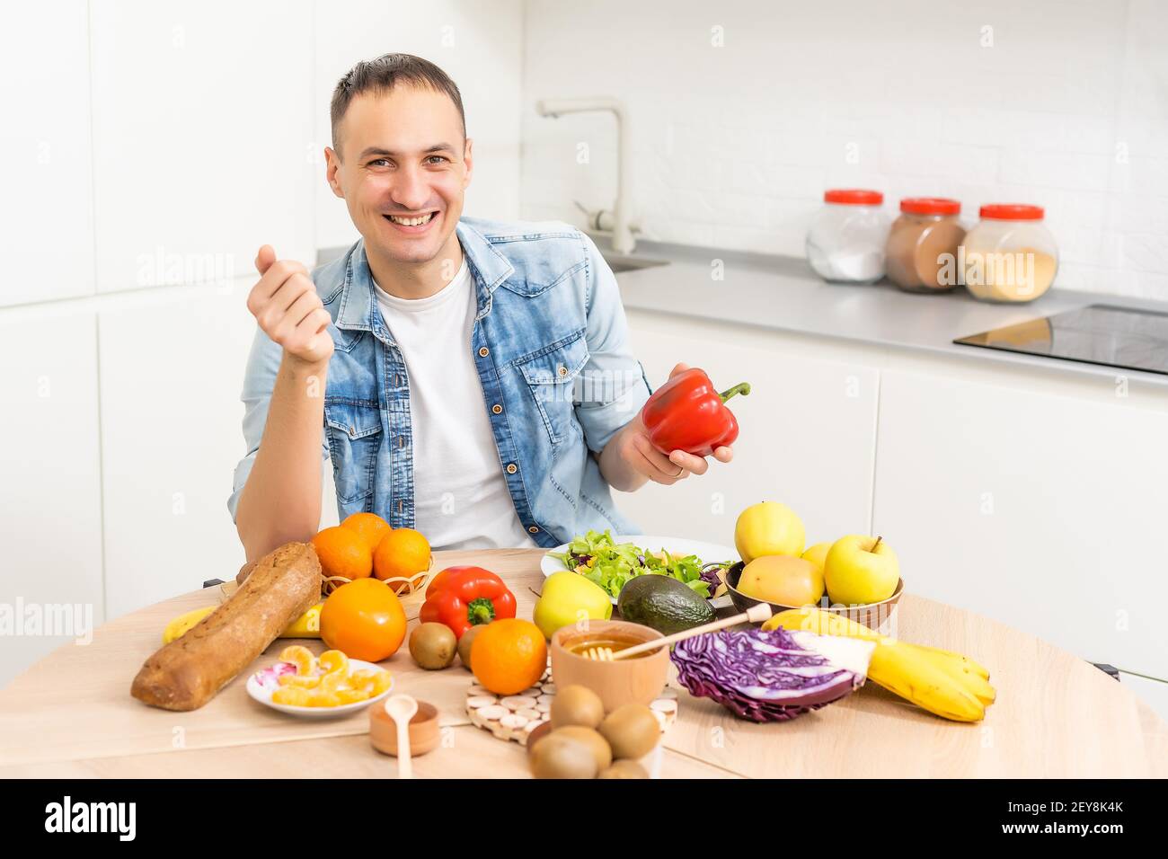 Joyeux jeune homme préparant un dîner romantique recherche de recettes de légumes Menu de régime, mari souriant cuisant la nourriture végétalienne saine salade coupée dans la cuisine Banque D'Images