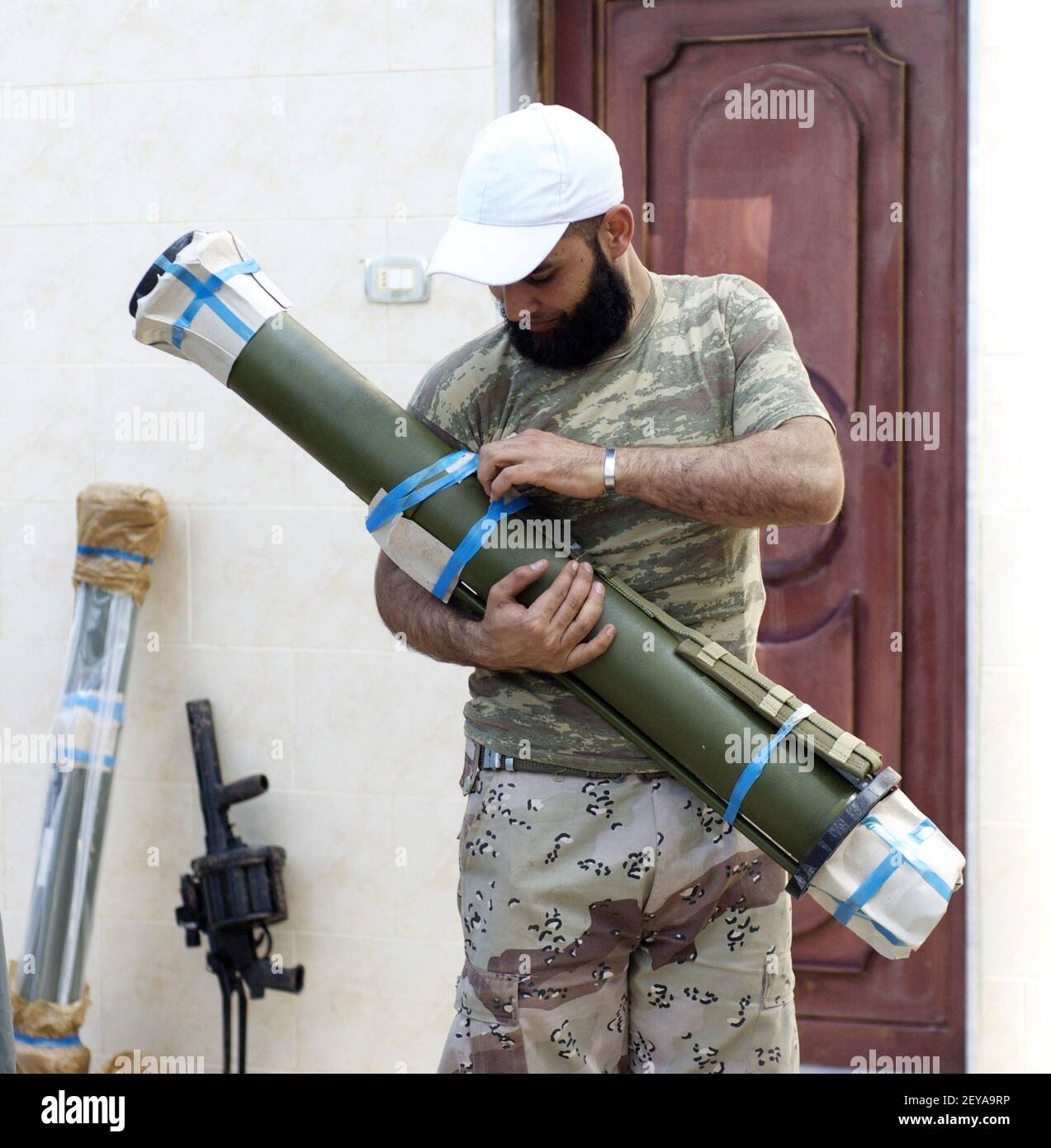 27 févr. 2013 - Kfar Nbouda, - Ahmed Darwish, commandant d'un groupe rebelle syrien appelé la Brigade Nasr, débouche un RPG-27 à Kfar Nbouda, Syrie, le 27 février 2013. Au cours des derniers mois, les rebelles ont acheté des armes plus avancées sur le marché noir et auprès de sponsors étatiques comme l'Arabie saoudite. Un lanceur de grenade RBG-6, qui fait partie d'une cargaison d'armes en provenance d'Arabie saoudite, repose contre le mur. Crédit photo: David Enders/MCT/Sipa USA Banque D'Images