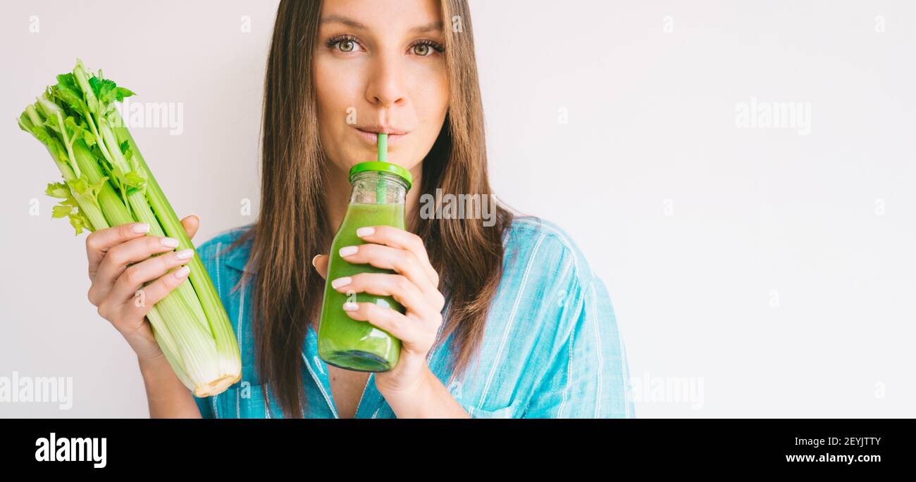 La femme tient un bouquet de branche de céleri frais et des boissons fraîches jus de céleri maison Banque D'Images