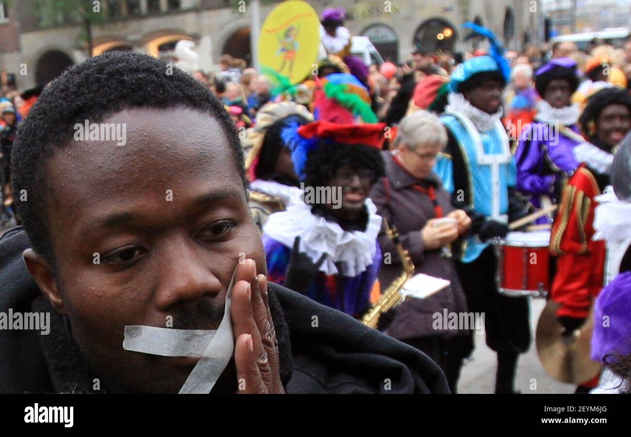Les manifestants avec une bande sur leur bouche et portant des t-shirts disant «Black Pete is Rascisme» tournent le dos à la procession lors de l'entrée traditionnelle de Saint Nicolas à Amsterdam, dans une protestation contre la figure traditionnelle Zwarte Piet (Black Pete), le 17 novembre 2013. Zwarte Piet est le compagnon de Saint Nicolas lors d'une fête annuelle célébrée le soir du 5 décembre. Il a été annoncé en octobre 2013 que l'Organisation des Nations Unies, sous l'autorité du Haut Commissaire aux droits de l'homme, enquêtait sur la question de savoir si Zwarte Piet est un stéréotype raciste. (Photo de Paulo Amorim/Sipa U Banque D'Images