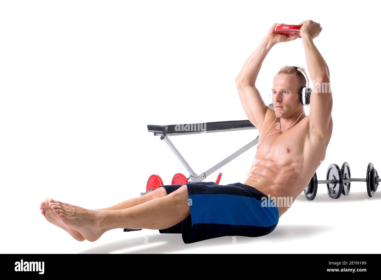 Un jeune homme blond musclé qui soulève des poids et écoute de la musique dans un casque Banque D'Images
