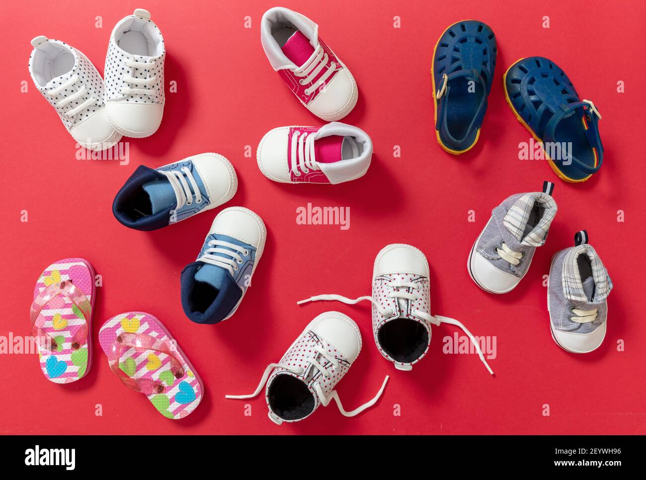 Bébé premiers pas. Variété de chaussures pour enfants sur fond rouge, vue du  dessus. Chaussures pour enfants, chaussons pour filles et garçons et  chaussures douces pour bébés, pose à plat Photo Stock -