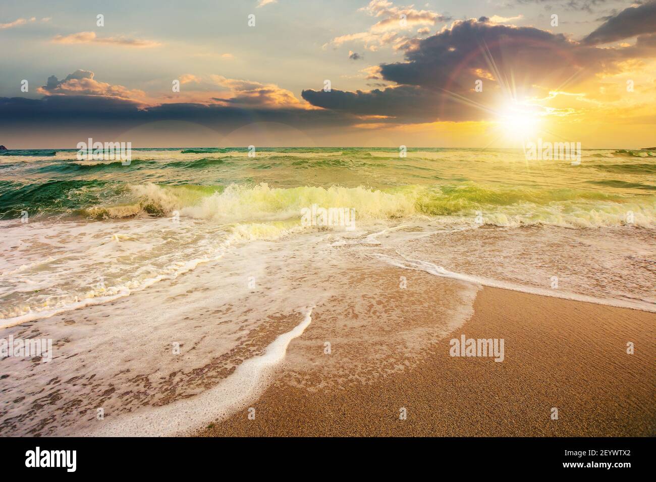 marée de mer sur un lever de soleil nuageux. vagues vertes écrasant la plage de sable doré sous la lumière du matin. temps d'orage approchant. concept de vacances d'été Banque D'Images