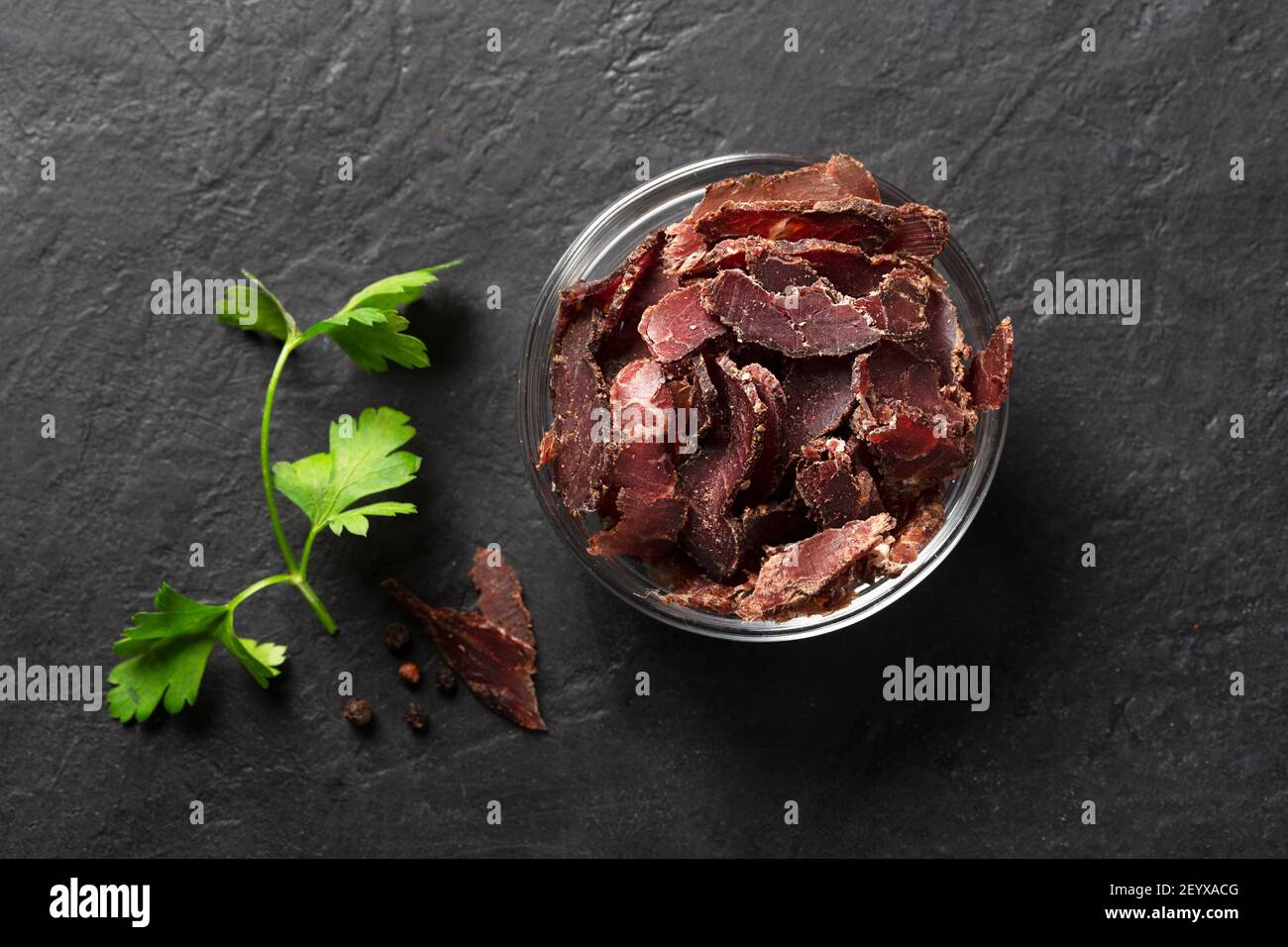 Bol avec viande jerky sur fond sombre, vue de dessus Banque D'Images